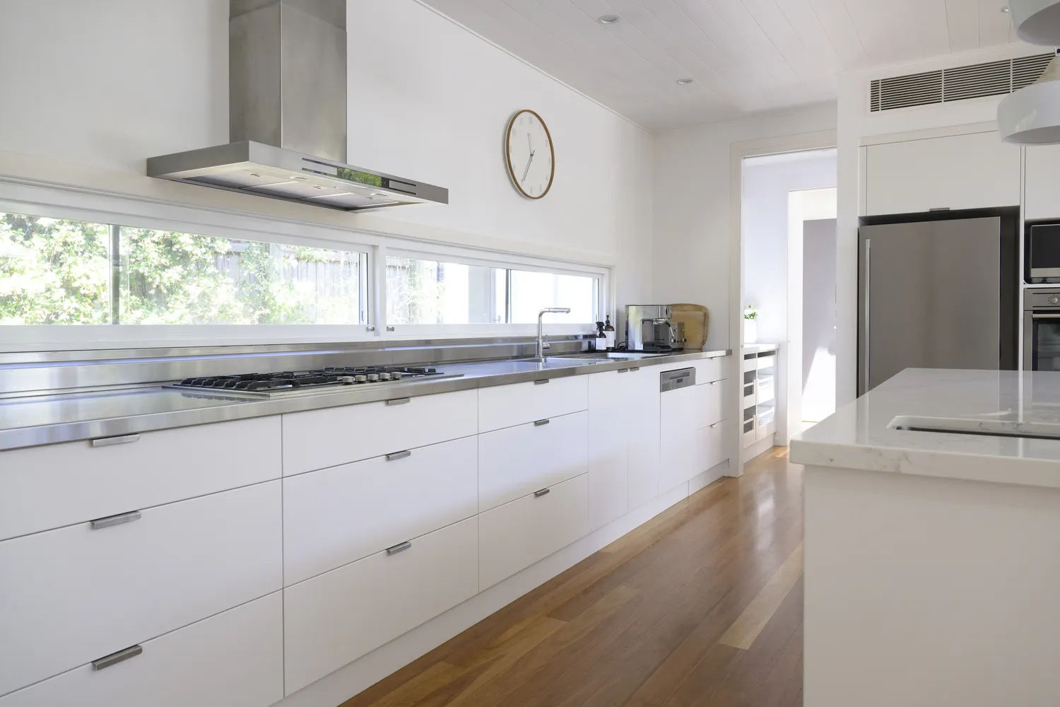 Modern kitchen with white flat-panel cabinets and wide wood flooring.