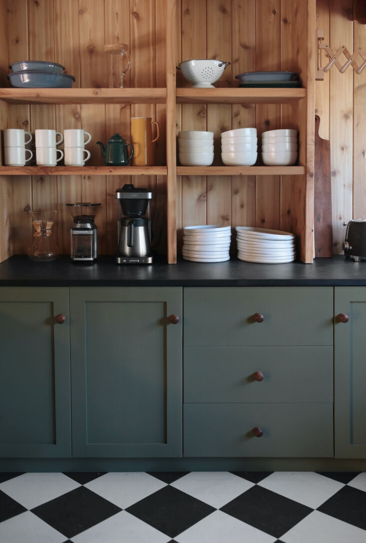 Close-up of green shaker-style kitchen cabinets and slab drawers.