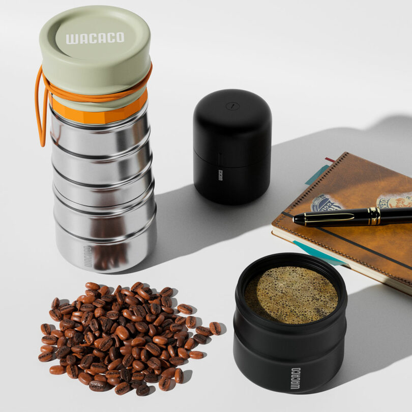 Top-down view of a MokaMax coffee maker, black canister, notebook, and a cup of coffee on a white desk.