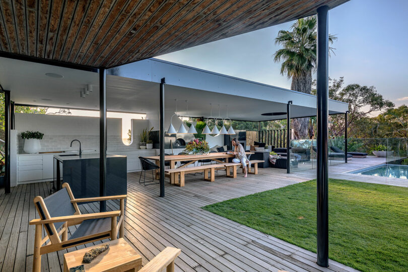 An expansive outdoor patio with distinct zones for dining, lounging by the pool, and sunbathing.