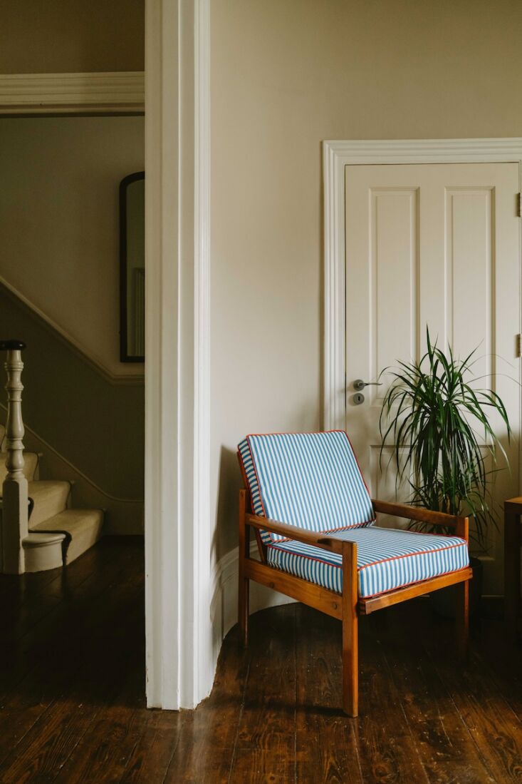 A vintage armchair upholstered in delicate green and white skinny stripes.