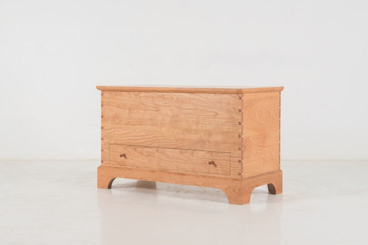 A handcrafted cherry wood blanket box featuring a lower drawer and traditional mortise and tenon joinery.