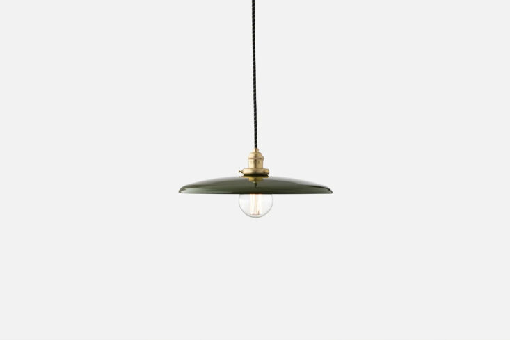 A natural brass disc pendant light hanging from a black cord.
