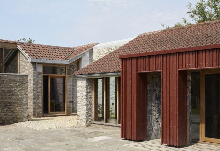Salvaged bricks arranged as a 'rug' on the ground between the old stone wall and a new extension.