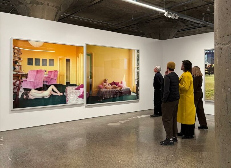 Visitors viewing large-scale photography in a modern art gallery with an industrial ceiling.