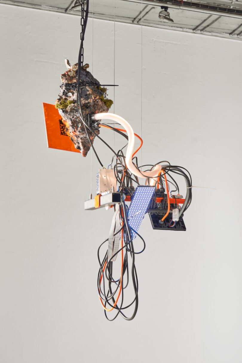Conceptual mixed-media sculpture with orange panels and exposed circuitry using modular elements.