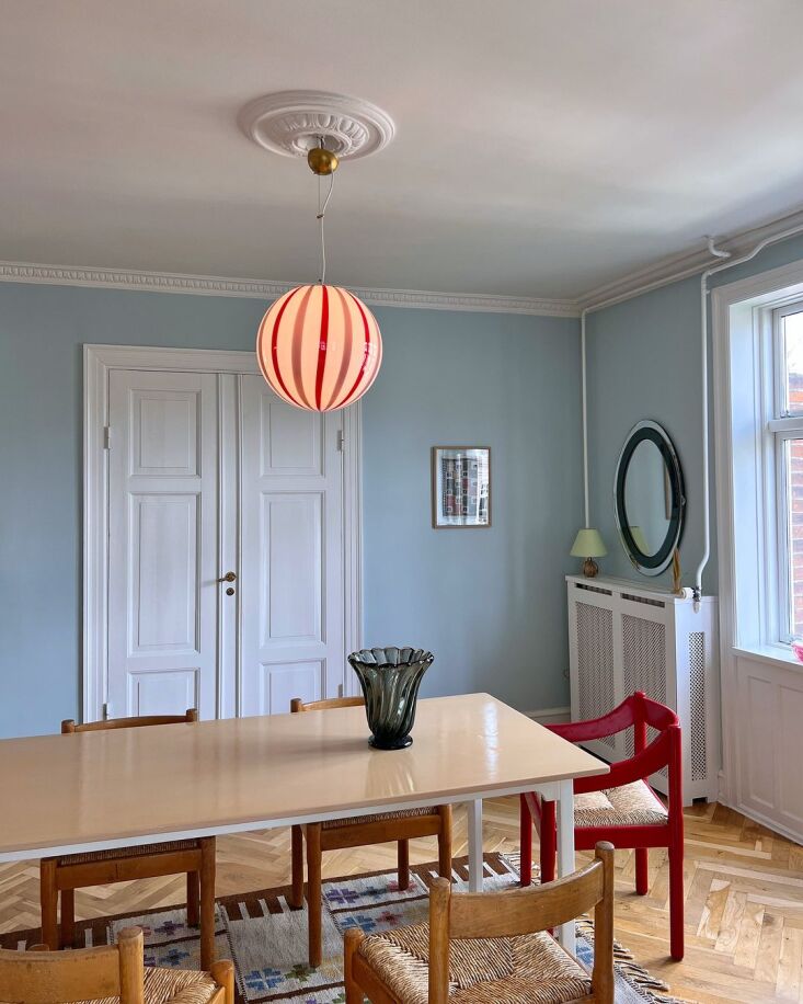 A collection of colorful striped Murano glass pendant lights hanging in the Millefiori Interior shop in Copenhagen.