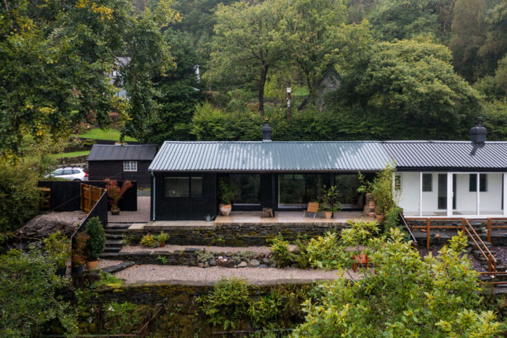 The rectangular bungalow featuring large picture windows compared to the smaller windows of the neighboring structure.