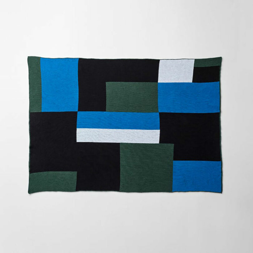 A textile with a geometric grid pattern featuring black, green, blue, and white rectangles.