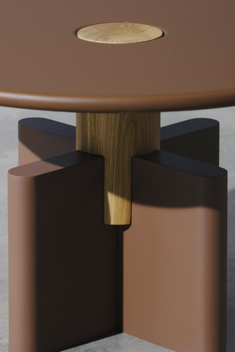 A round brown drum-style coffee table with a geometric base on a concrete floor.