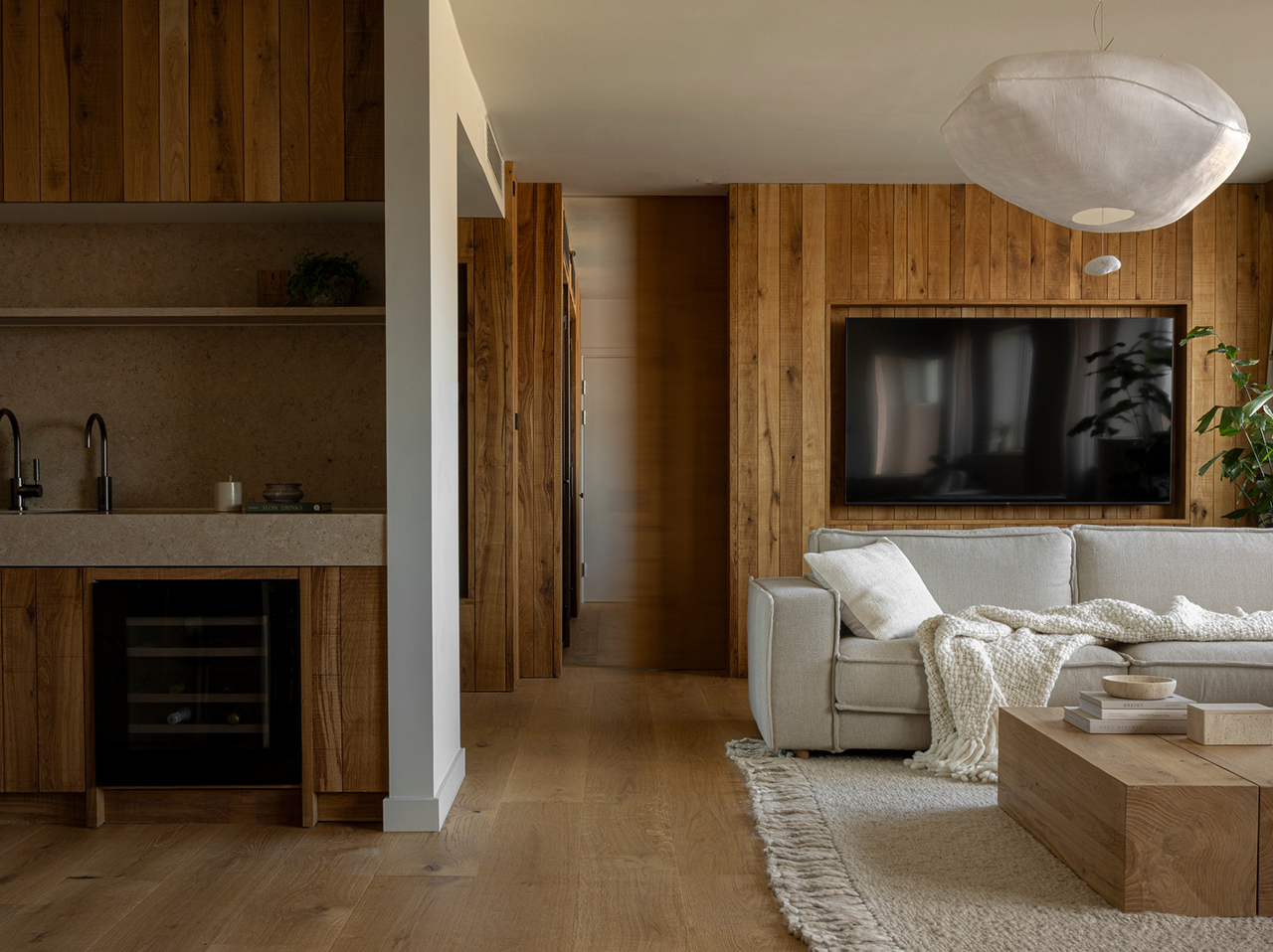 A luxury suite interior featuring a sleek kitchenette, comfortable sofa, and warm wood-paneled walls.