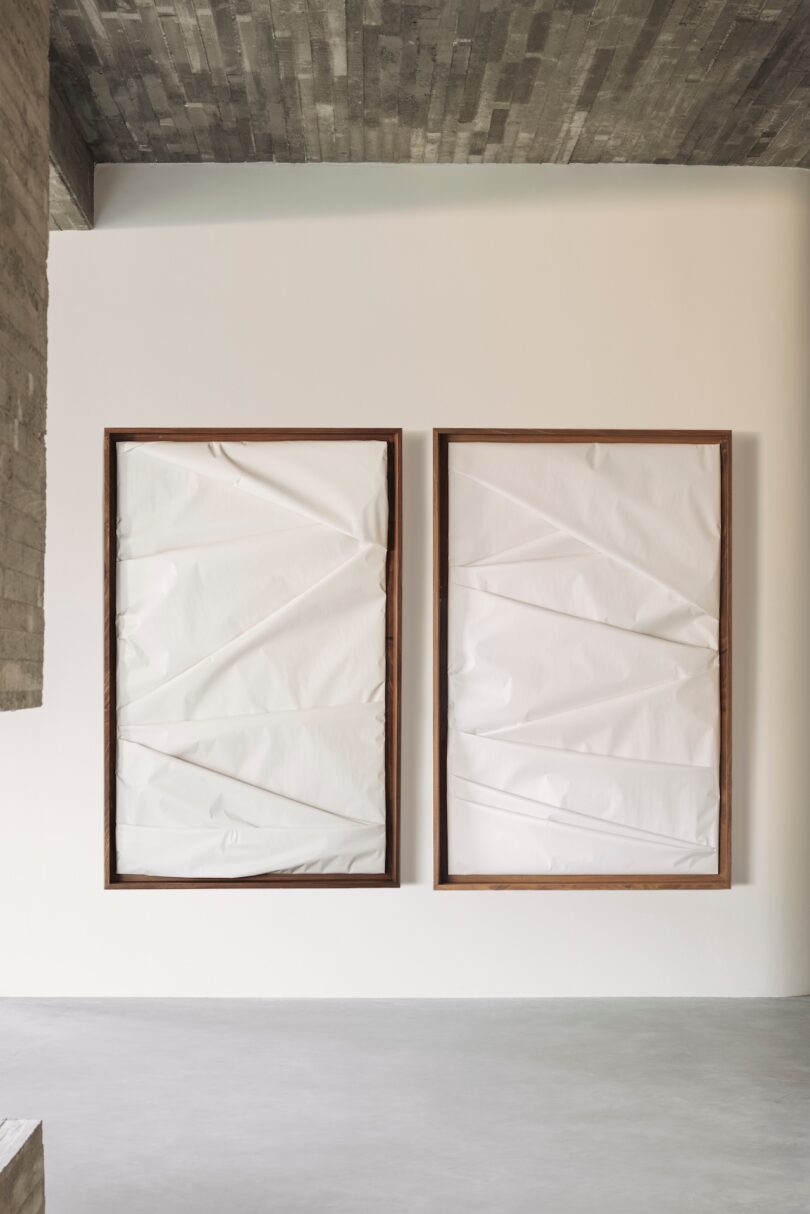 Two wooden frames containing crumpled bio-cellulosic material hung on a minimalist wall.