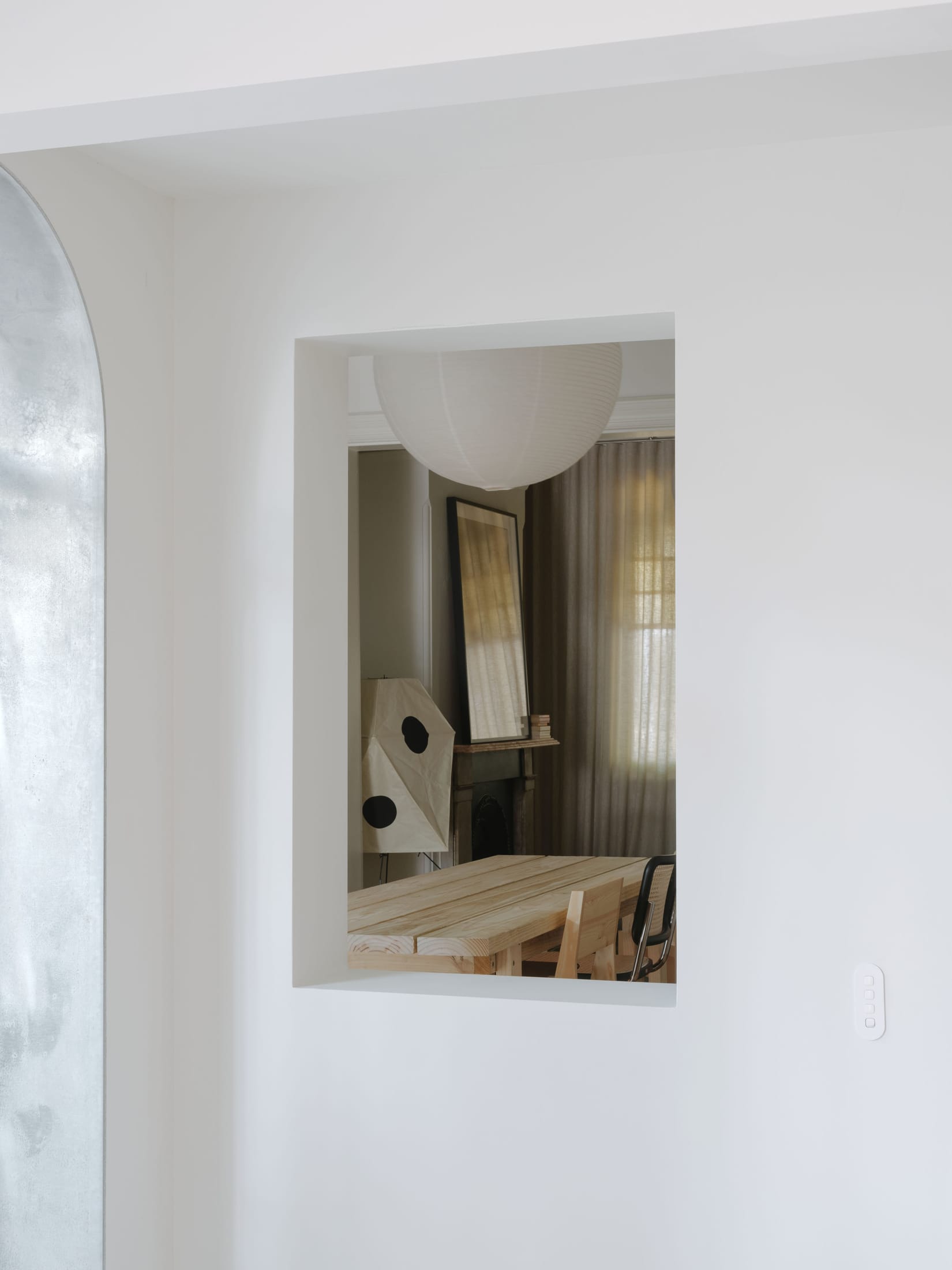 Interior view showing dappled light filtering through a steel mesh screen into a living room.