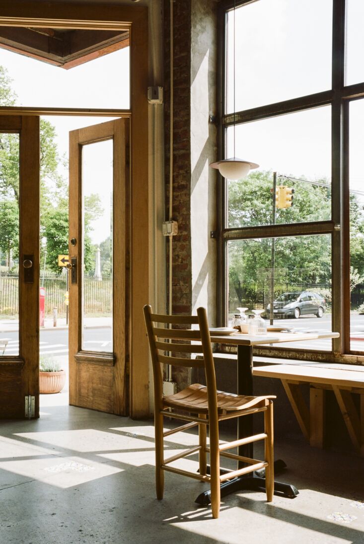 Interior view of the pizzeria featuring custom cold-rolled steel windows, exposed brick walls, and modern pendant lighting.