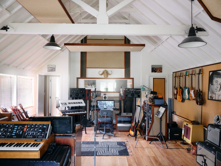 A professional recording studio setup inside a room with warm wooden acoustic treatments.