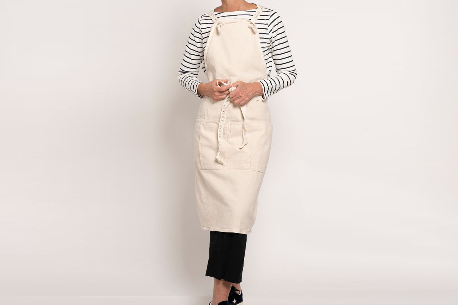 A sturdy natural canvas utility apron with metal hardware.