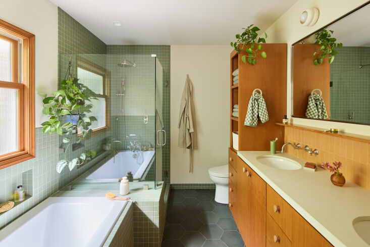 A bathroom with green hexagon floor tiles and vertical wall tiles.