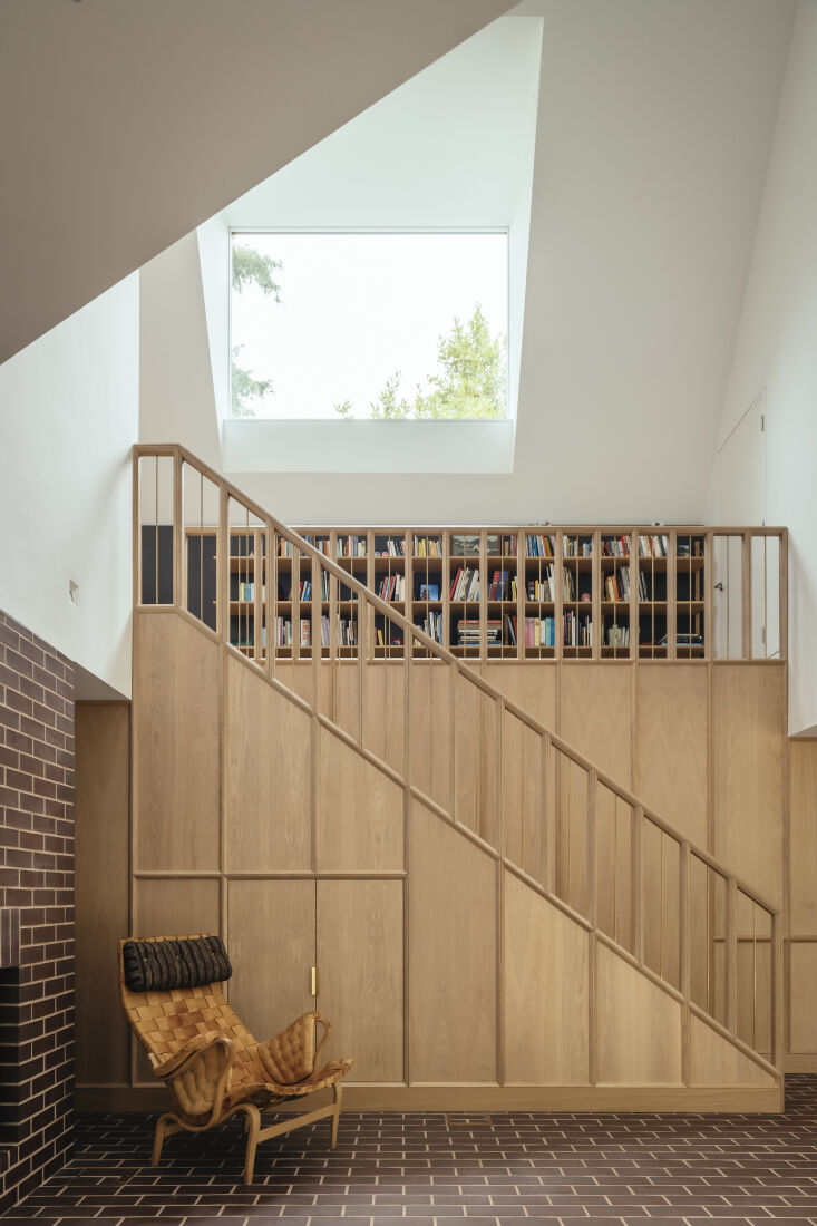 A triple-height hallway with a bespoke European Oak staircase and brown Staffordshire brick flooring.