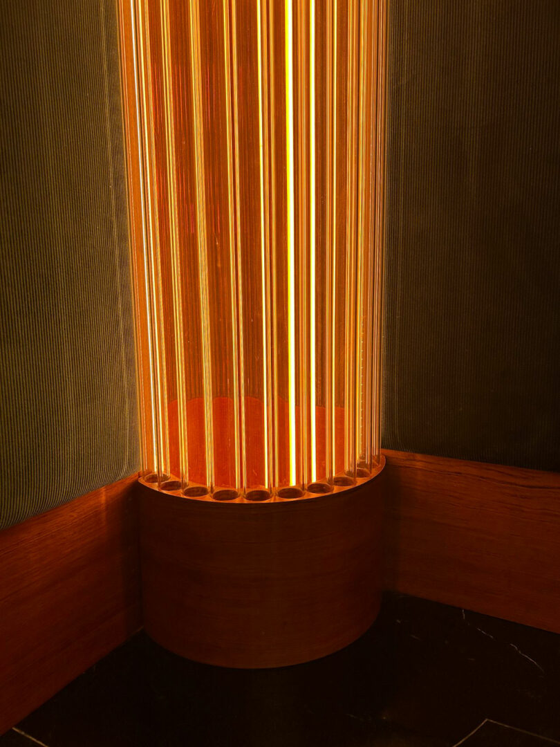 A glowing cylindrical floor lamp casting soft, textured shadows in a corner.