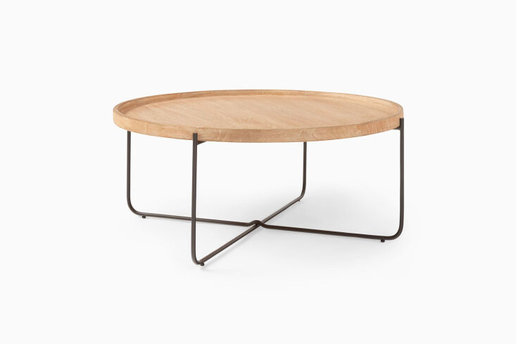 West Elm Willow Round Coffee Table featuring a warm wood finish and tapered legs.