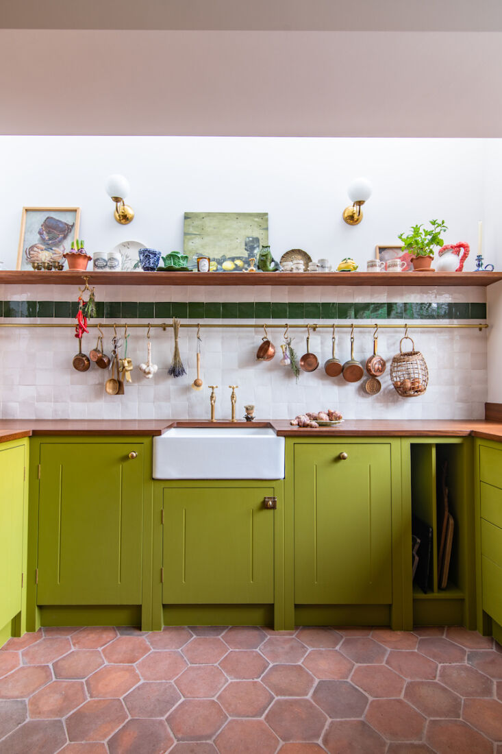 British Standard kitchen cabinetry with a brass rail for hanging copper pots.