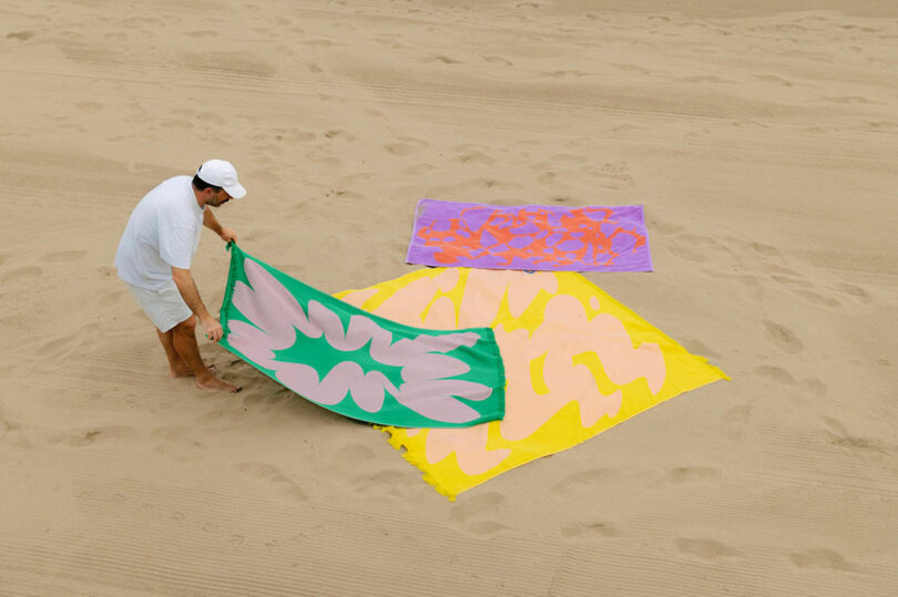 Brightly colored, patterned towels spread out on a sandy beach.