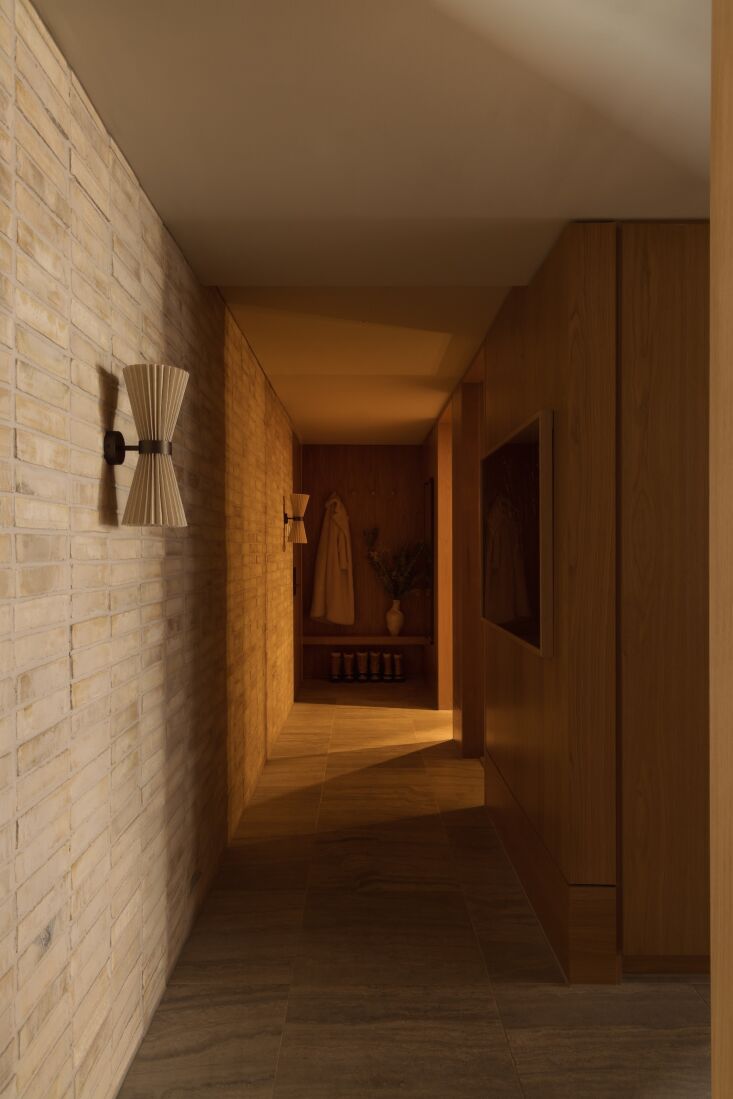 The entry hall of the ski chalet featuring matte-glazed pale bricks, wood paneling, and travertine floor tiles.