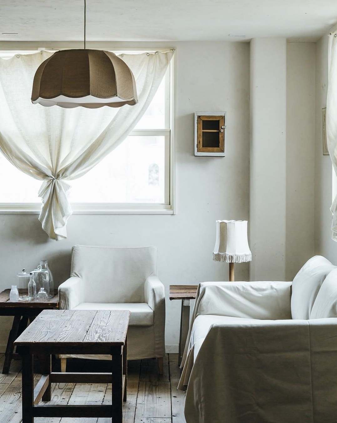 A linen Flower pendant light paired with an Alma Fringe table lamp on a wooden base.