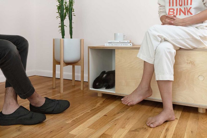 An angled view of a wooden bench furniture piece designed to house a rabbit cage.