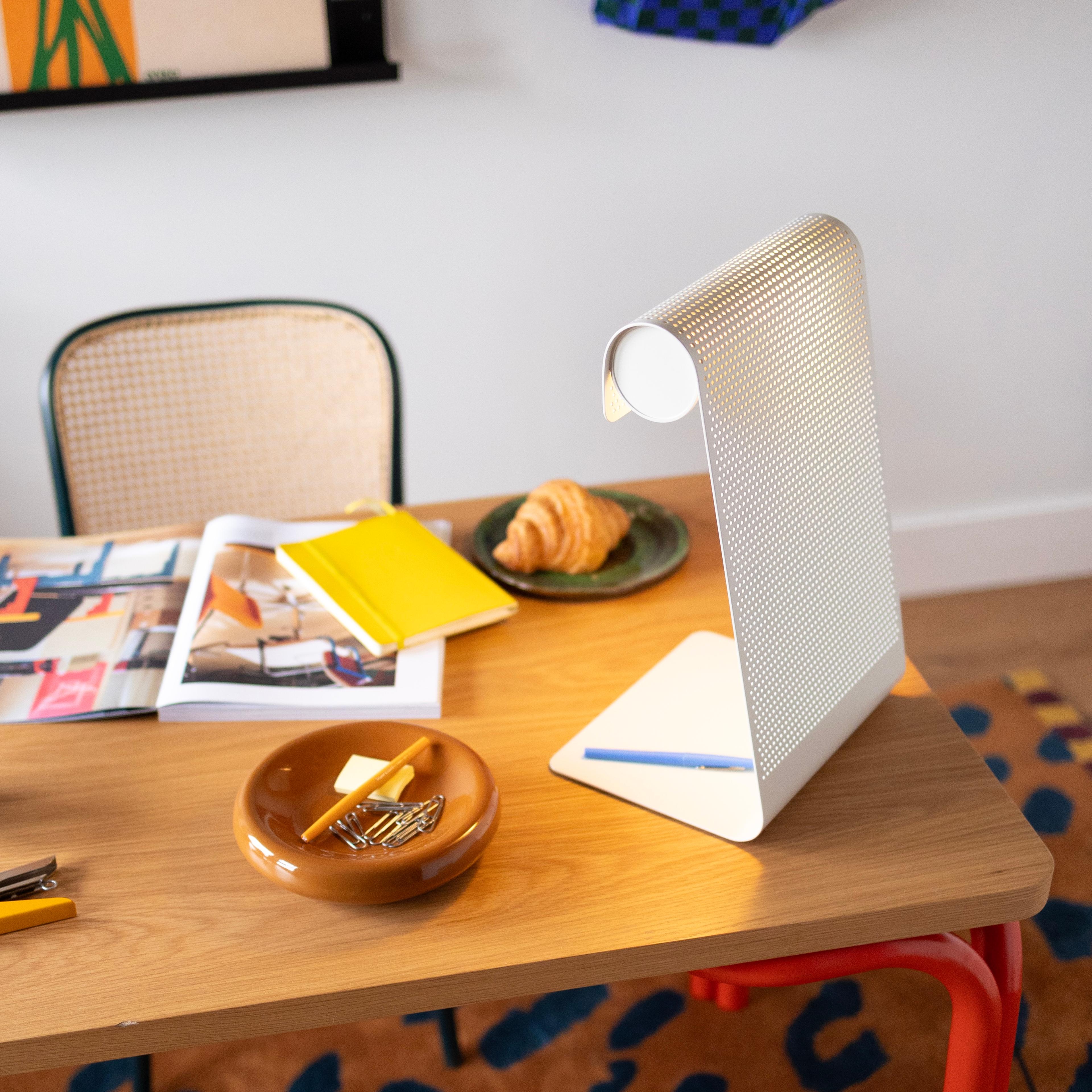 A classic schoolhouse-style desk lamp providing focused light on a workstation.