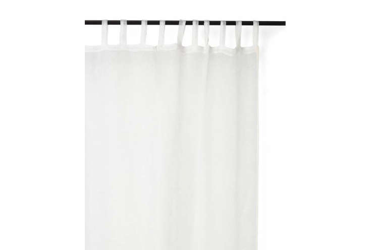 White netted linen curtains hanging in front of a window, diffusing sunlight.