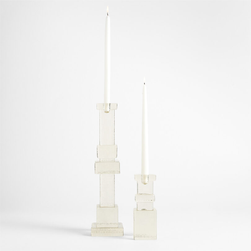 Two white geometric taper candle holders of different heights with white candles.