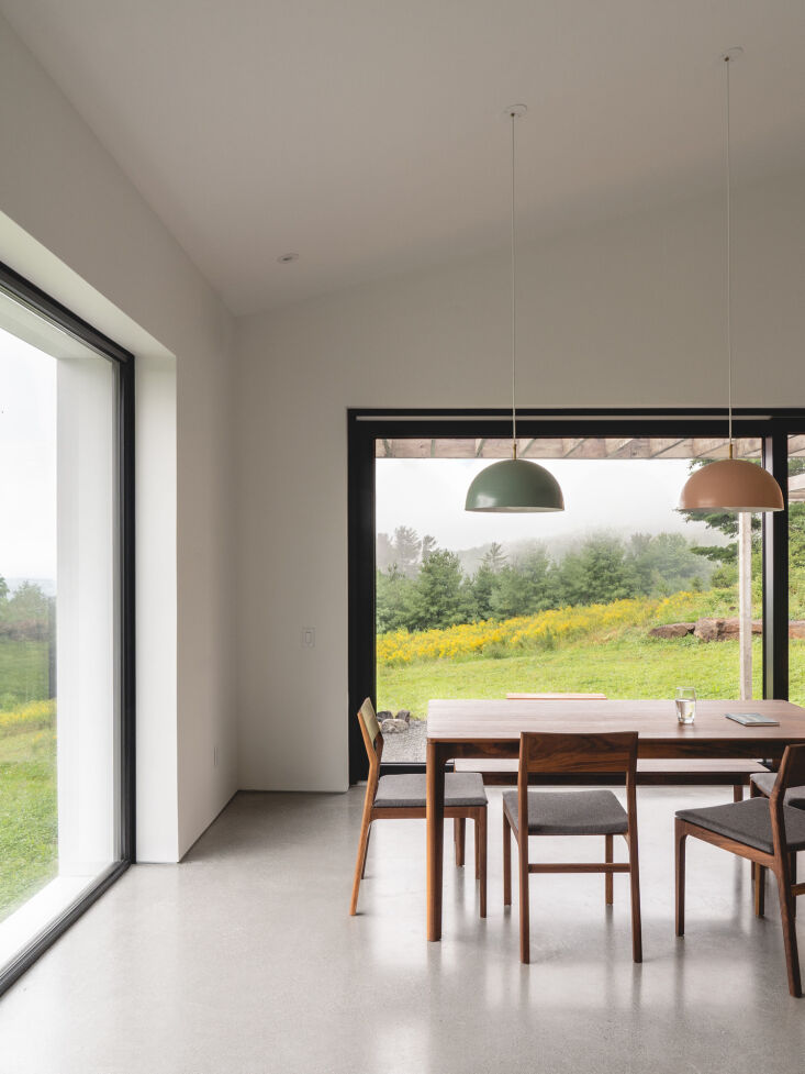 Dining area with a black walnut table and large windows looking out onto the Québec forest.