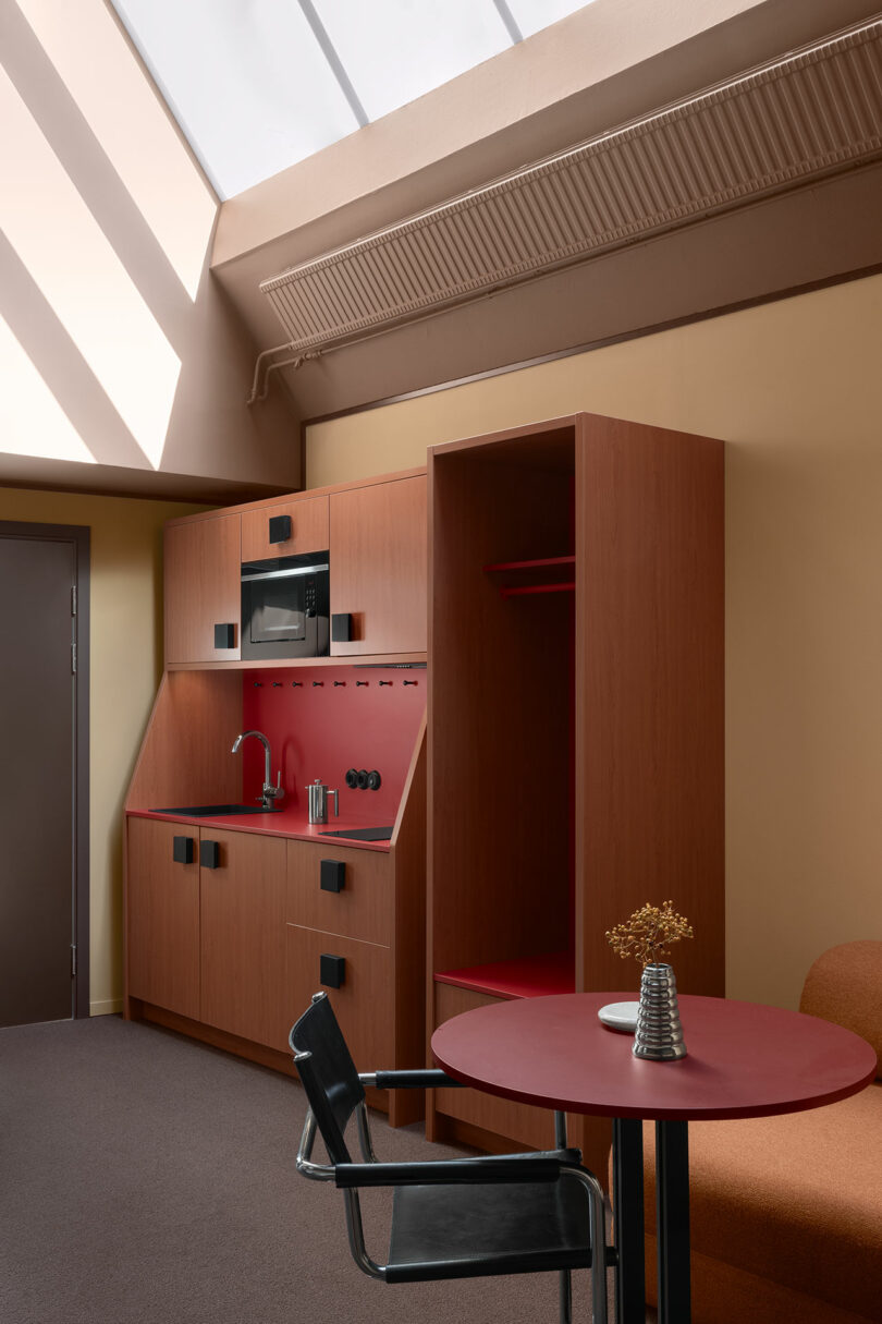 A compact kitchenette with wooden cabinets and a round dining table under a skylight.