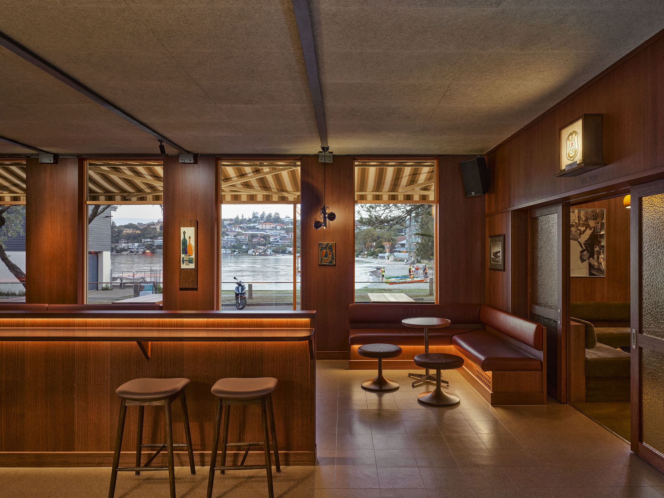 A sleek, 1950s airport lounge-style bar area with atmospheric lighting and retro furniture.