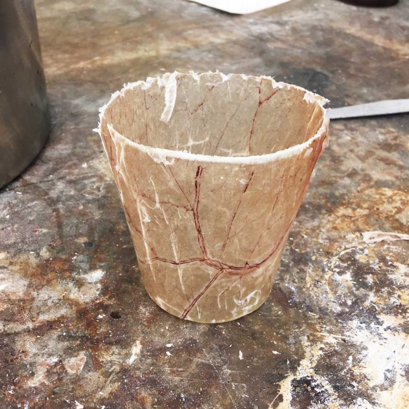 Close-up of a veiny, textured organic cup resting on a concrete floor.