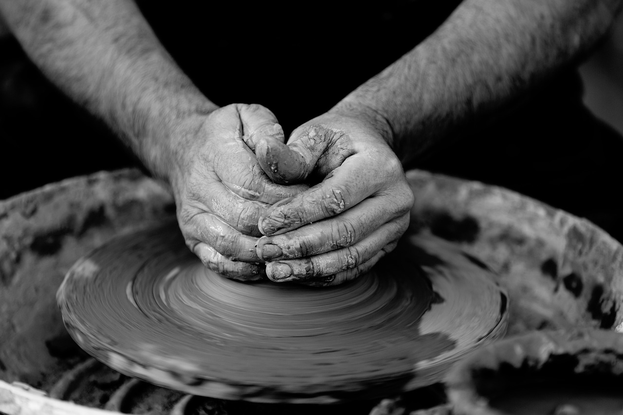 Hands working with clay to create small pottery pieces during a home gathering.