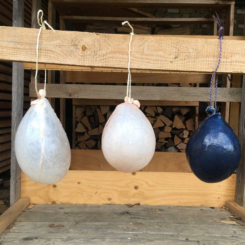 Translucent balloon-like objects hanging from wooden studs to dry.