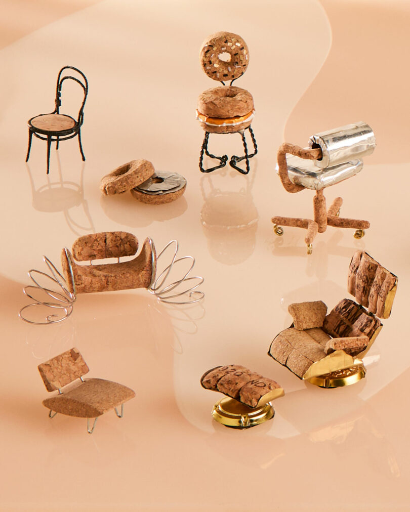 A group of diverse miniature chairs crafted from cork and wire on a beige background.