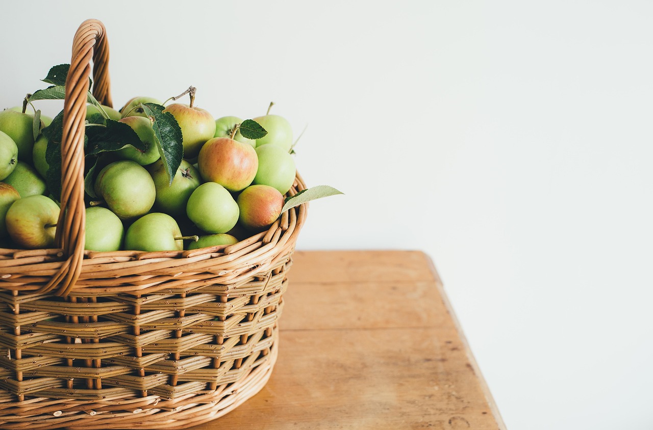 A wooden table decorated with linen napkins, fresh pears, and rosemary sprigs.