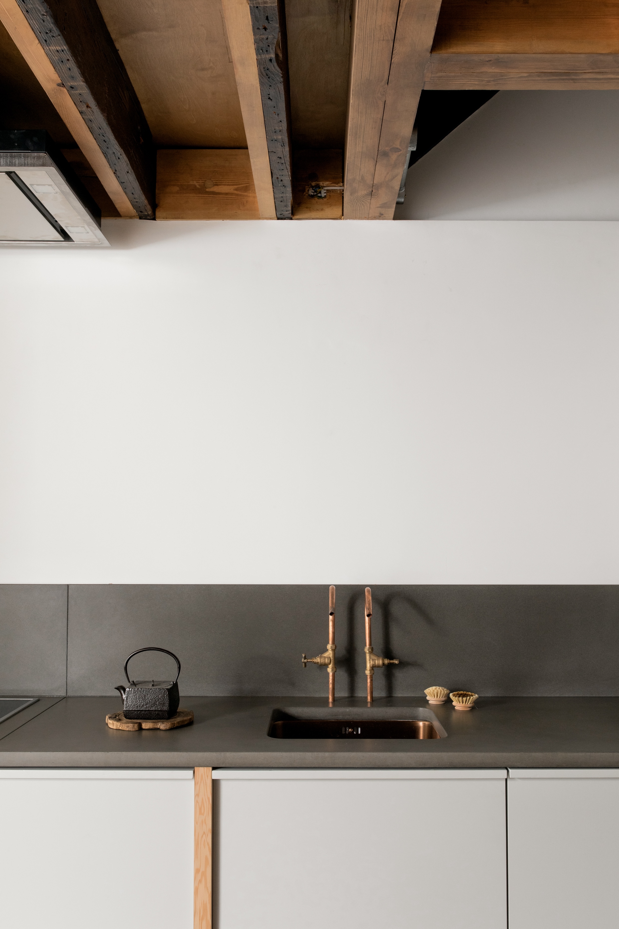 Detail of copper piping faucets and a mix of old and new ceiling joists.