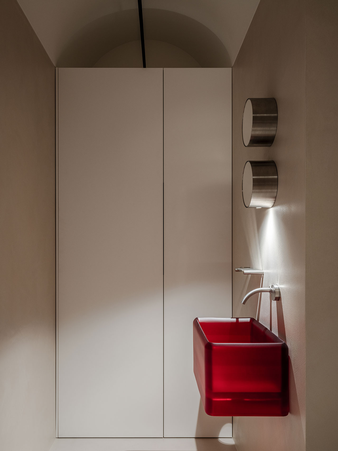 Minimalist bathroom featuring a striking red rectangular pedestal sink and wall-mounted faucet.