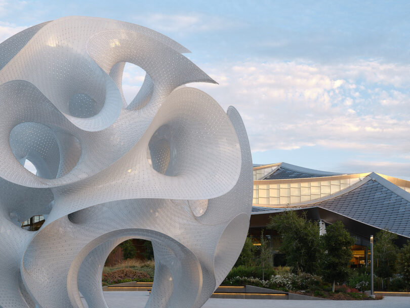 A wide shot of the white sculptural Orb standing in front of the glass-roofed Charleston East Google building.