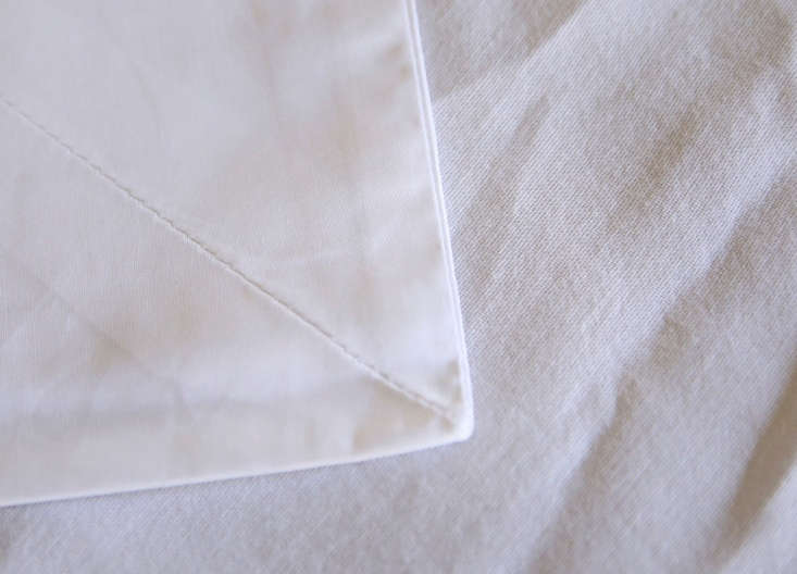 A close-up comparison showing the tight, fine weave of Sferra fabric at the top versus a looser, coarser budget weave at the bottom.