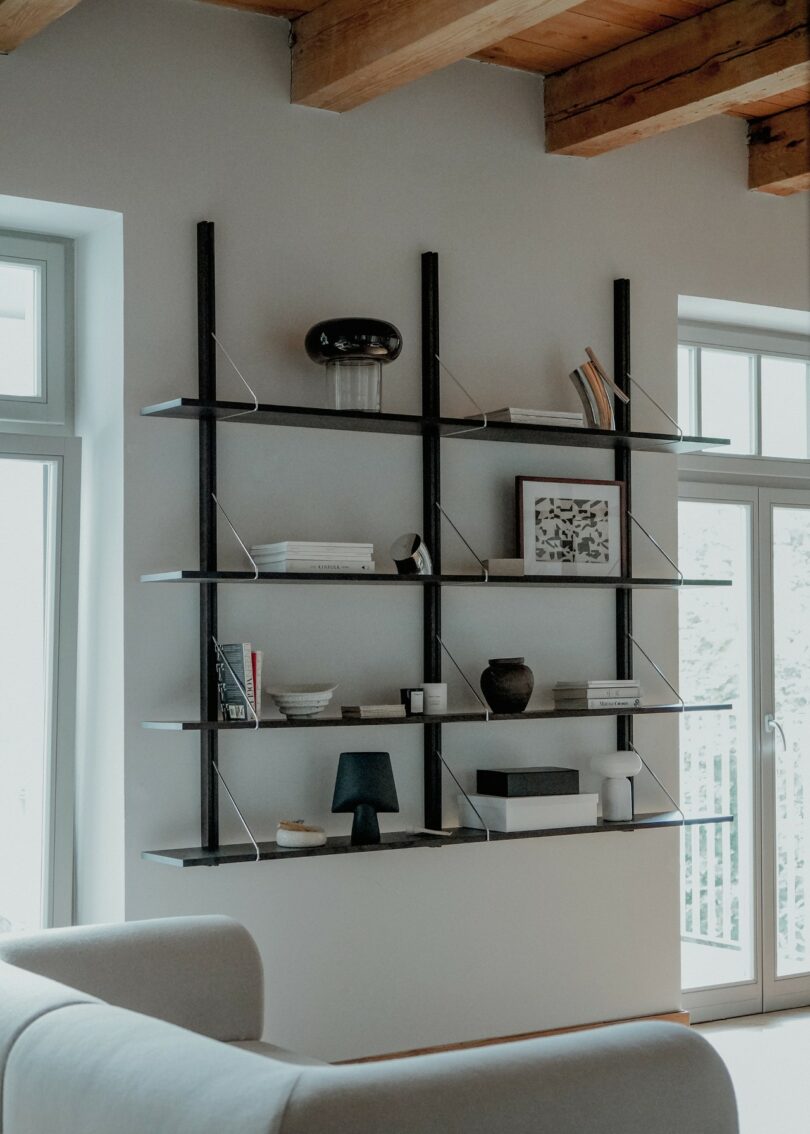 Wall-mounted shelving unit in a room with high ceilings and exposed wooden beams.
