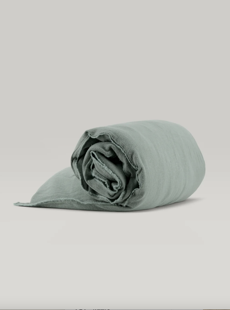 A sofa covered in a vibrant green Verveine linen topper for a relaxed, chic look.