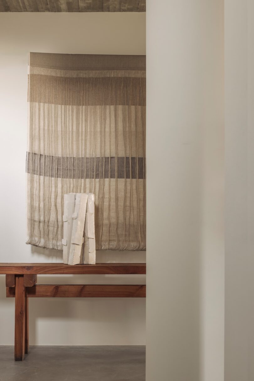 A neutral-toned textured wall hanging paired with a smooth white sculptural object.