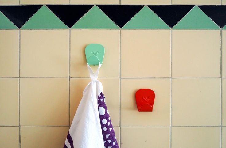 Close-up of adhesive hooks successfully mounted on different textures including wood and subway tile.