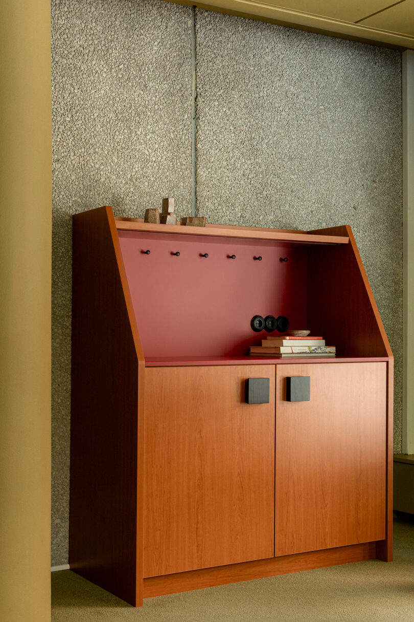 A wooden cabinet with a red back panel and multiple electrical outlets integrated into the shelving.