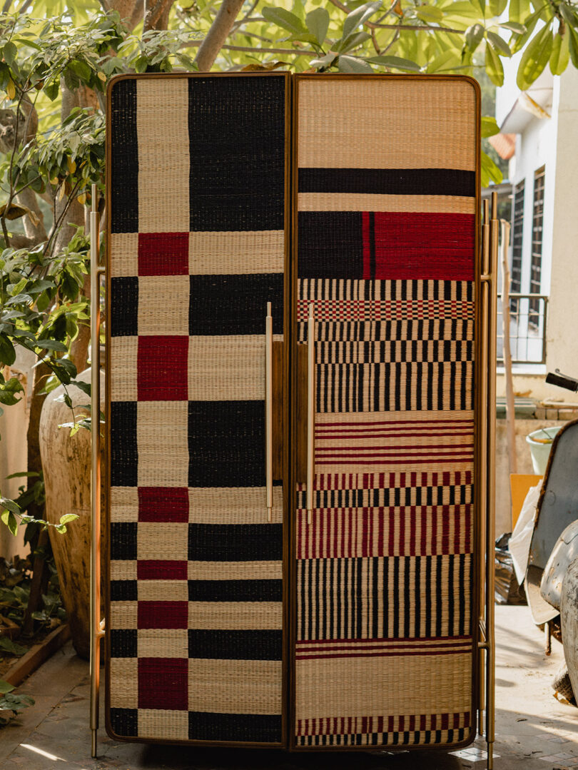 A modern cabinet featuring doors with intricate black, red, and beige woven geometric patterns.
